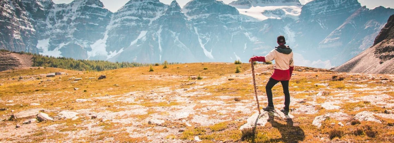 A young person with a trekking stick looking out to the mountains, representing the Explore course at All Nations.