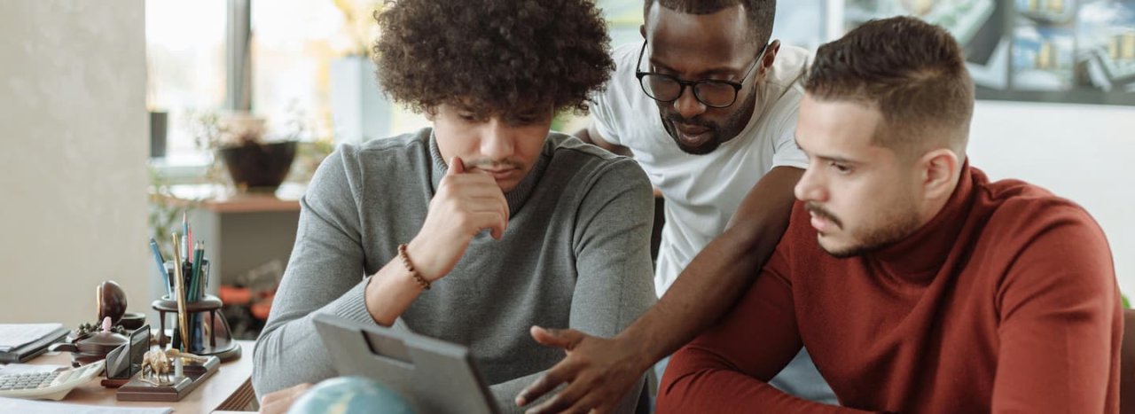 A group of young men from different backgrounds in a workplace, led by the central person, representing the course for intercultural coach run by All Nations.